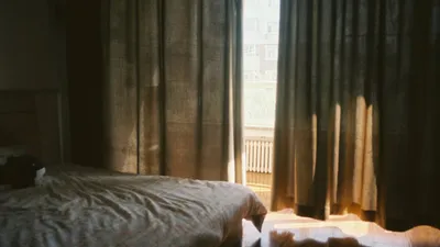 Warm bedroom featuring sunlit curtains and a peaceful, cozy ambiance.