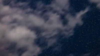 A serene night sky filled with stars and scattered clouds, perfect for astronomy lovers.