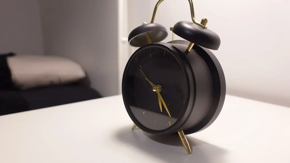 Vintage-style black alarm clock on modern minimalist bedside table in a cozy bedroom.