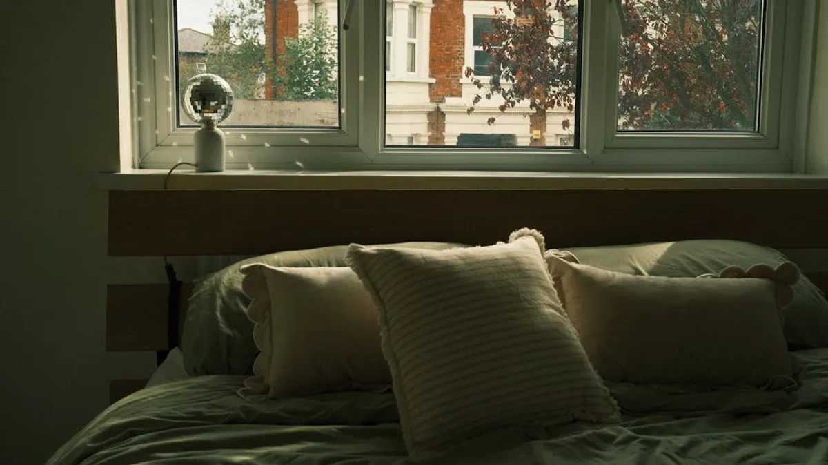 Cozy bedroom with soft pillows and a window view in autumn. Inviting atmosphere.