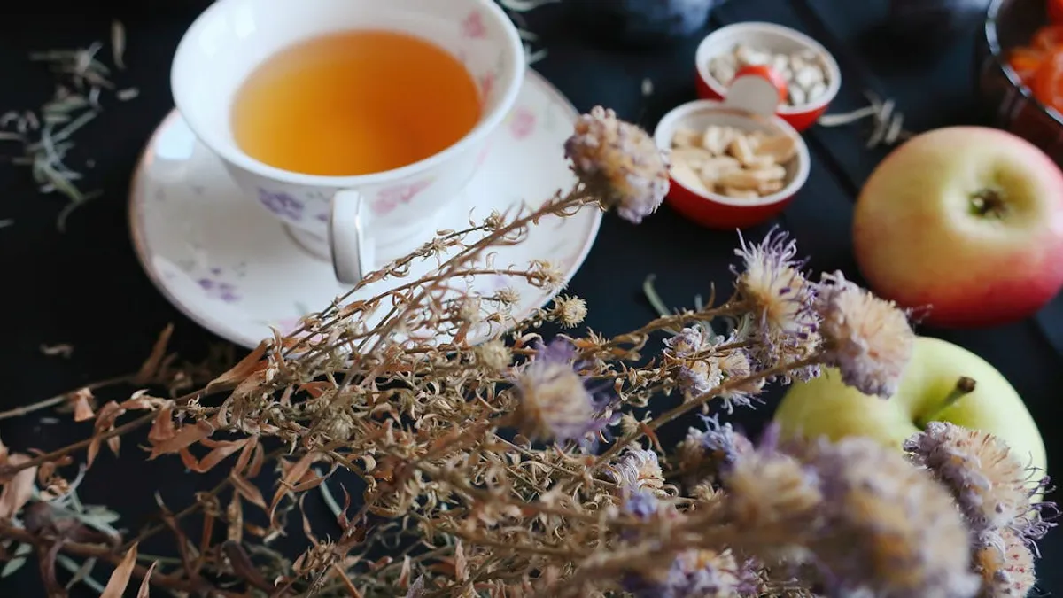 Elegant tea cup with apples and dried flowers on a dark setting, perfect for a cozy breakfast scene.