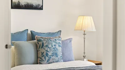 A serene bedroom featuring elegant decor, plush cushions, and soft lamp lighting for a cozy ambiance.