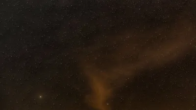 A mesmerizing view of a starry night sky with wispy clouds illuminated softly, perfect for backgrounds.